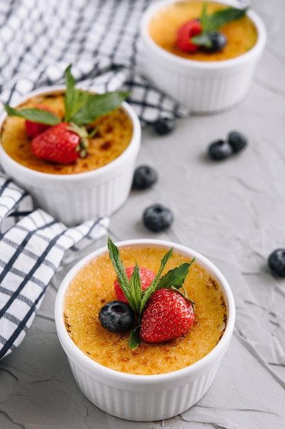 Cup of creme brulee with dessert plug and mint leave with berries