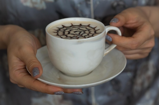 A cup of decorated latte in female hands