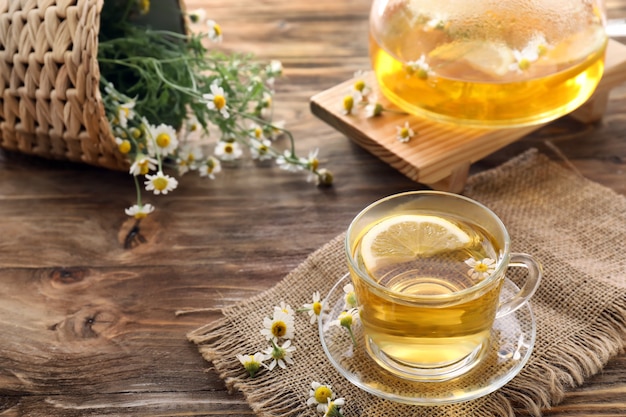 Cup of delicious camomile tea on wooden table