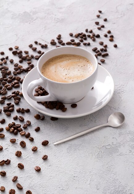 A cup of delicious hot cappuccino and beans on a gray concrete table