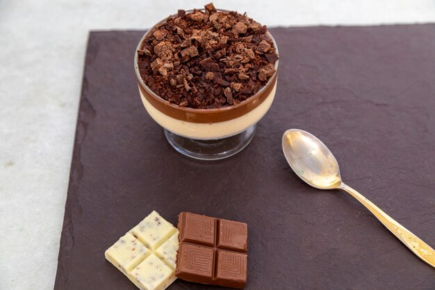 Cup of dessert with milk chocolate mousse with white chocolate\
shavings