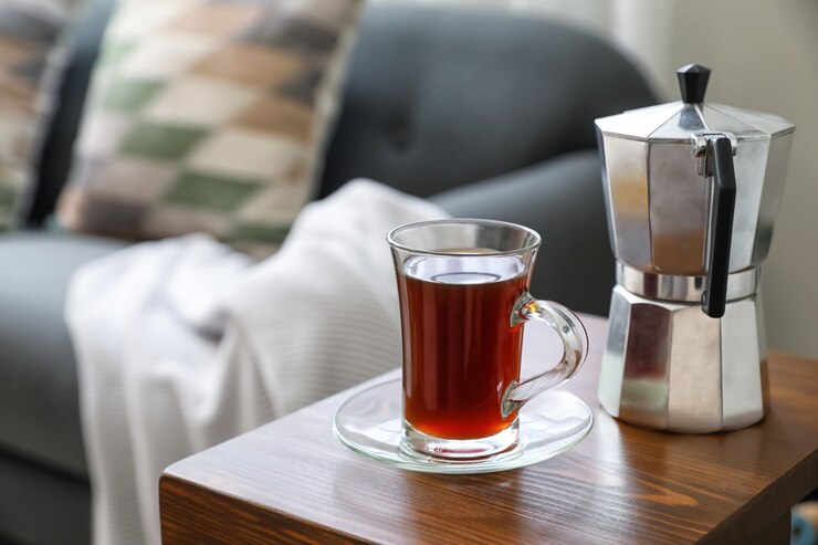 Photo cup of drink and coffee pot on armrest table in room