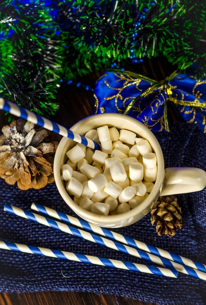 Cup of drink with marshmallows on christmas decoration