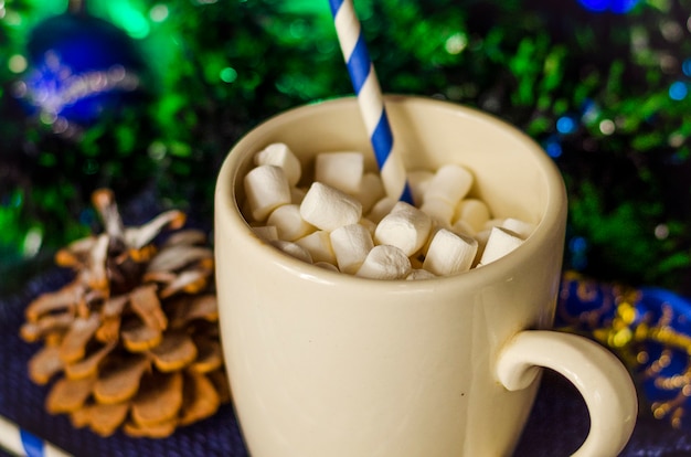 Cup of drink with marshmallows on christmas decoration