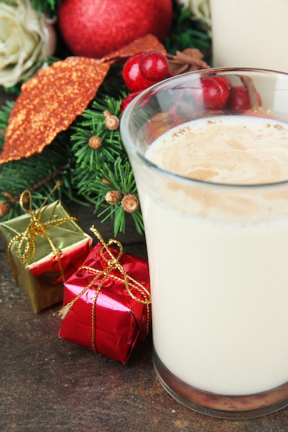 Cup of eggnog with fir branches and Christmas decorations close up