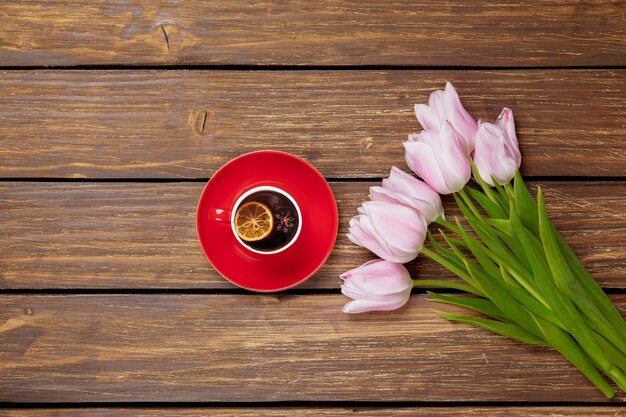 Cup of english tea with spring tulips on wood