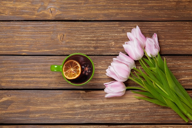 Cup of english tea with spring tulips on wood