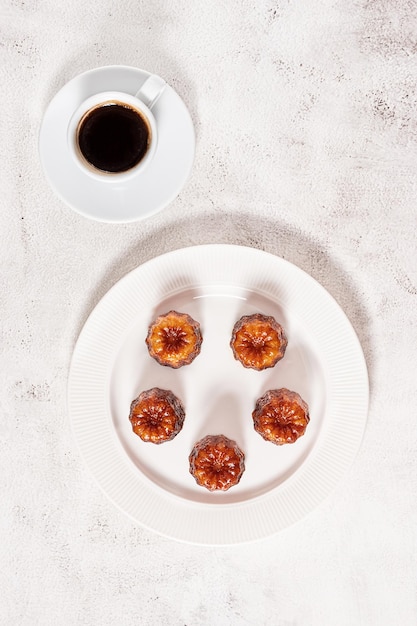 A cup of espresso coffee and local French dessert canele flat lay on grey concrete background