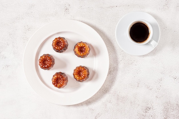 A cup of espresso coffee and local French dessert canele flat lay