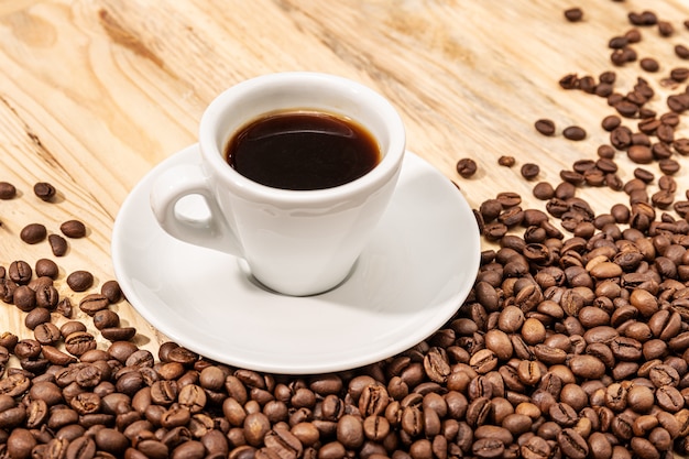 Cup of Espresso Coffee and roasted beans on wooden table.  Copy space.