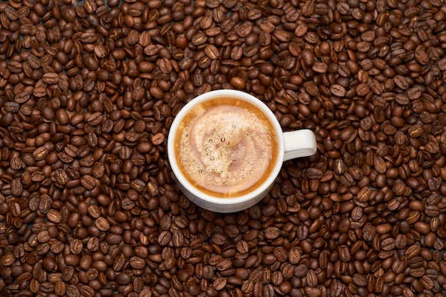 Cup of espresso coffee on roasted brown coffee beans