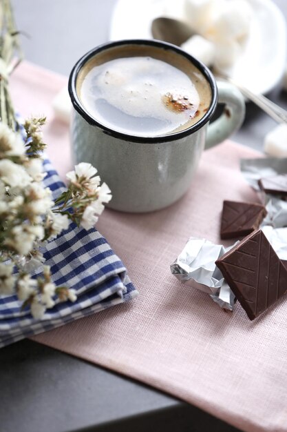 Cup of flavored coffee with chocolate on table with napkin closeup