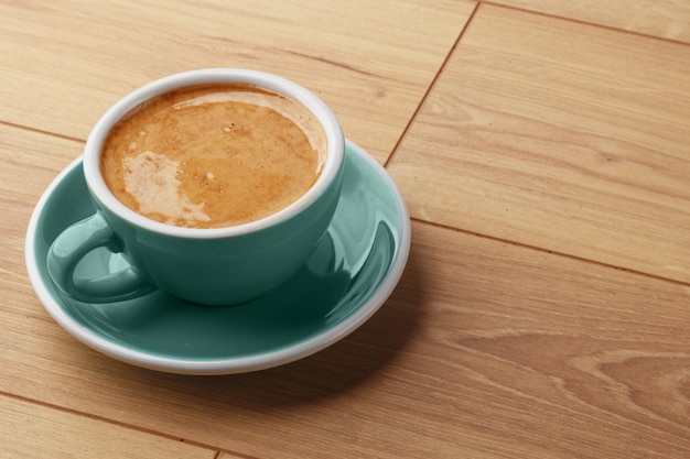 A cup of fragrant coffee in foam on a wooden table.