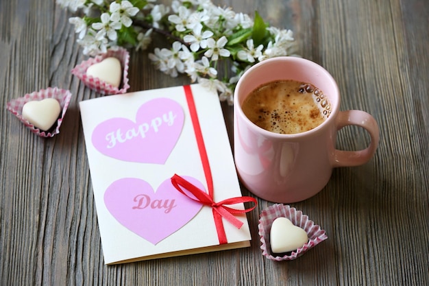 Cup of fresh coffee and card on wooden background