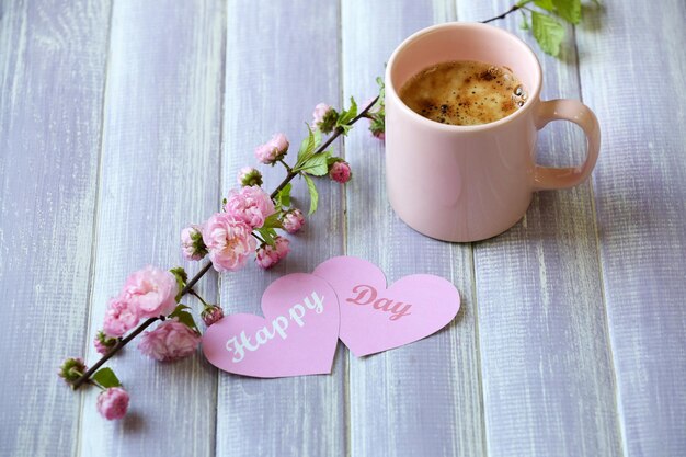 Cup of fresh coffee and cards on wooden background