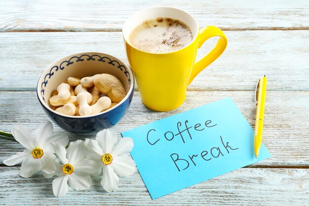 Cup of fresh coffee and note on wooden background