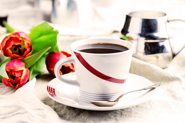 Cup of fresh coffee onl linen napkins Tulips next to cup