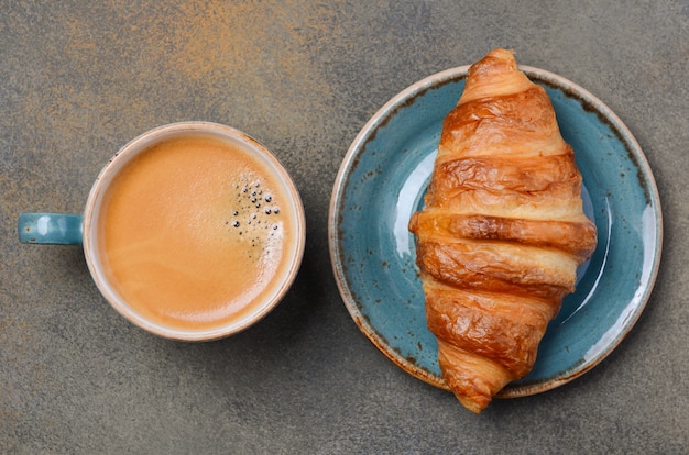 Cup of fresh coffee with croissant.