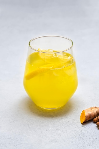 Cup of fresh homemade ginger turmeric lemonade on neutral background