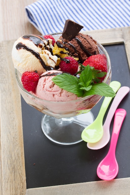 Cup of fresh mixed  icecream with berries and chocolate served on table