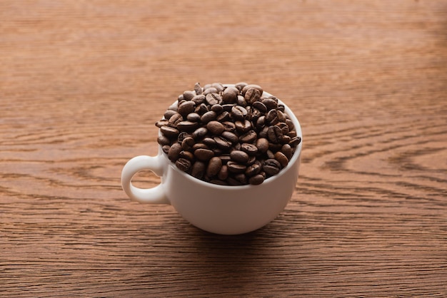 Cup of fresh roasted coffee beans on wooden table