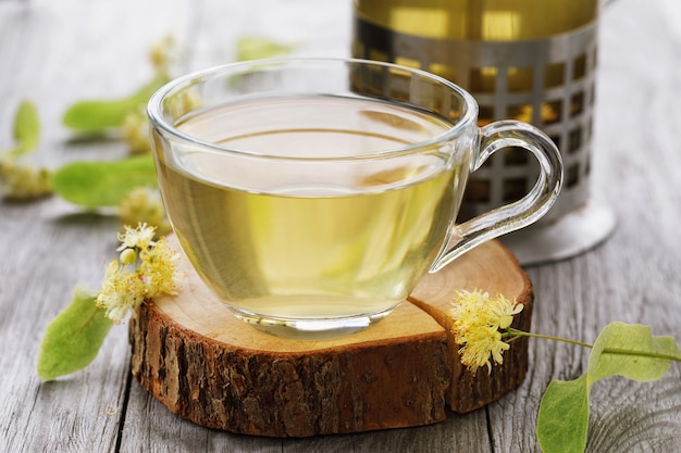 Cup of fresh tea made from linden leaves on a wooden stand