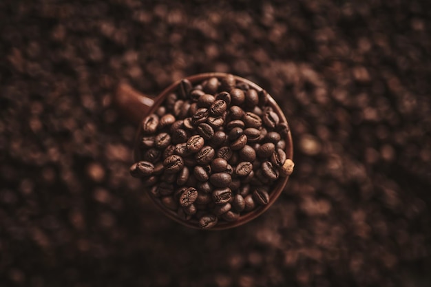 Cup of freshly brewed roasted coffee beans on brown background