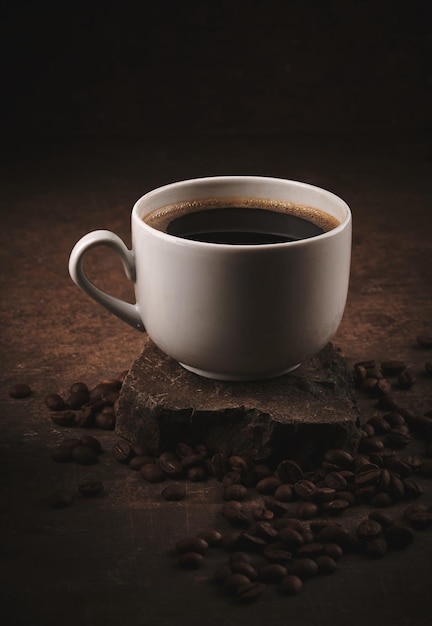 Cup of freshly brewed roasted coffee beans on brown background