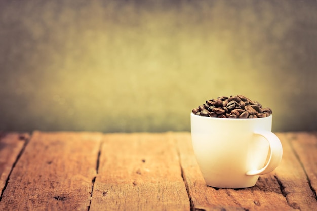 Cup full of coffee beans on wood table