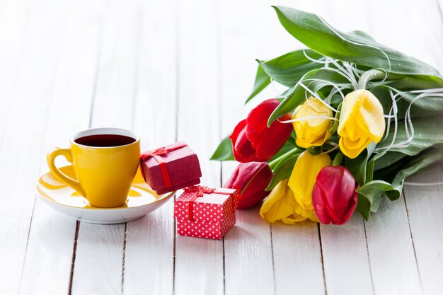 Cup and gift box with bouquet of tulips