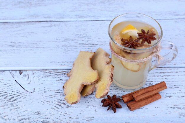 Cup of ginger drink with lemon on wooden background