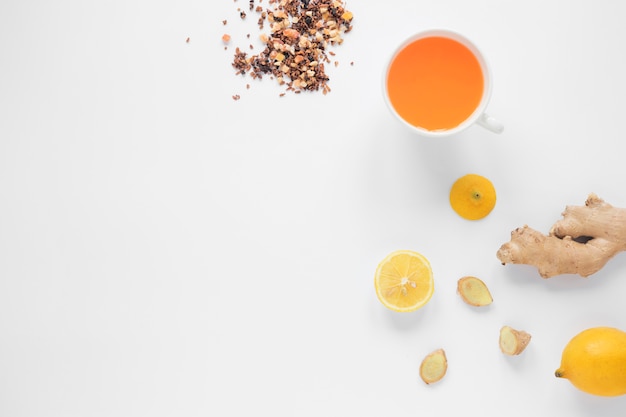 Tazza di tè allo zenzero; limone; erbe e miele su sfondo bianco