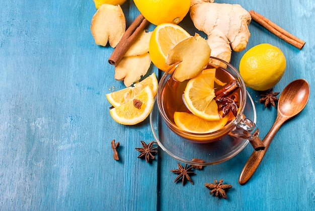Tazza di tè allo zenzero con limone e miele su sfondo blu scuro,