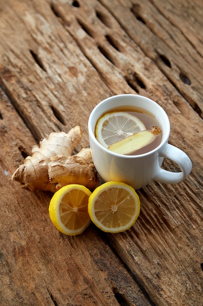 Cup of ginger tea with lemon on wooden