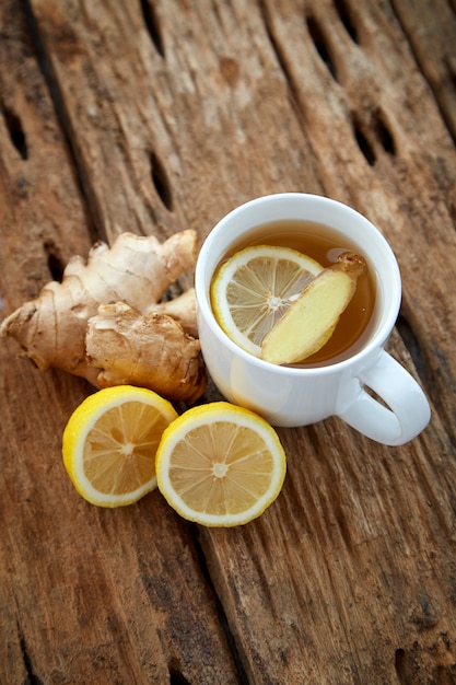 Cup of ginger tea with lemon on wooden