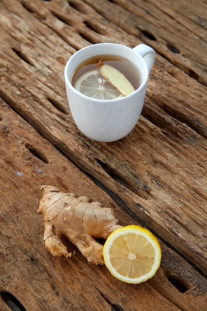 Cup of ginger tea with lemon on wooden