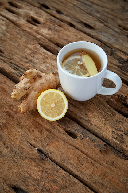 Cup of ginger tea with lemon on wooden