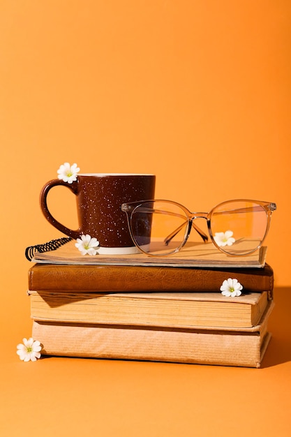 Cup and glasses on books on yellow background