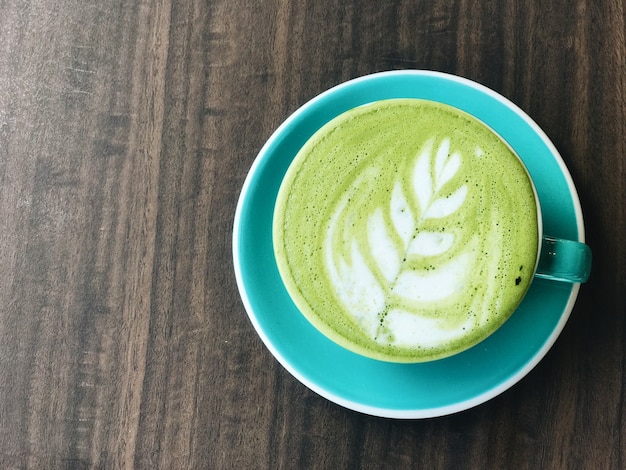 Cup of green matcha latte coffee on white table. Top view.