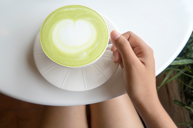 白いテーブルに緑の抹茶ラテコーヒーのカップ。上面図。