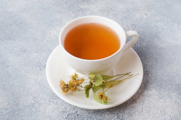 一杯の緑茶と花は灰色の表面にリンデンします。スペースをコピーします。