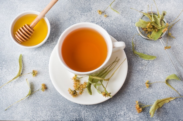 一杯の緑茶と花は灰色の表面にリンデンします。スペースをコピーします。