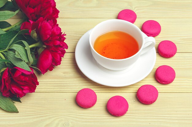 Cup of green tea on table with fresh peony flowers