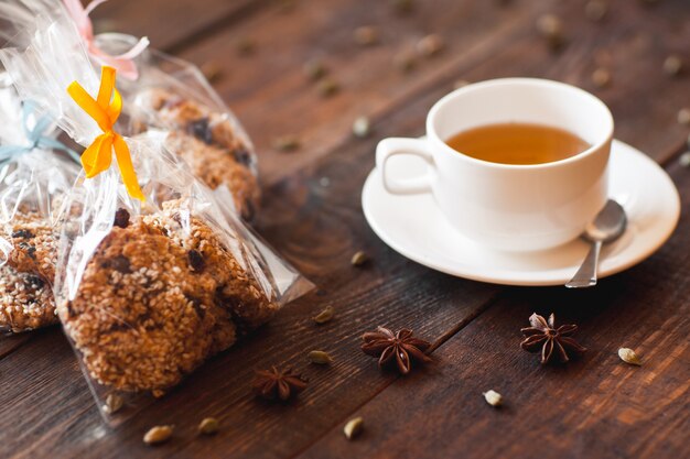 Cup of green tea with cookies spices on wooden table