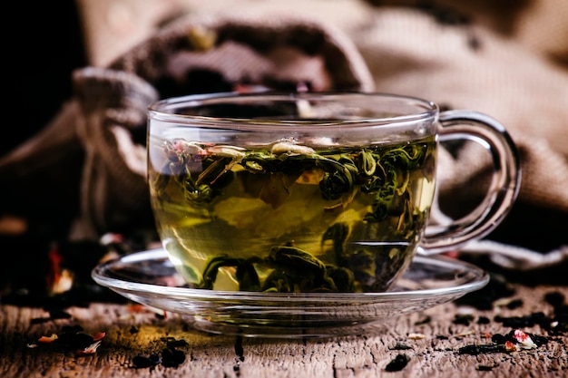 Cup of green tea with flower petals and fruits vintage wooden background selective focus