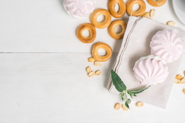 Cup of green tea with sweets, top view. bagels, nuts and tender marshmallows on a light