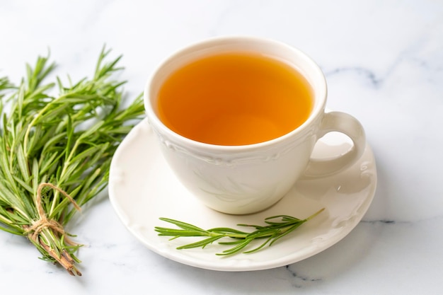 Cup of healthy rosemary tea with fresh rosemary bunch on rustic background, winter herbal hot drink concept, salvia rosmarinus