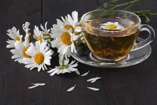 Photo cup of herbal chamomile tea with fresh daisy flowers on wooden background. doctor treatment and prevention of immune concept