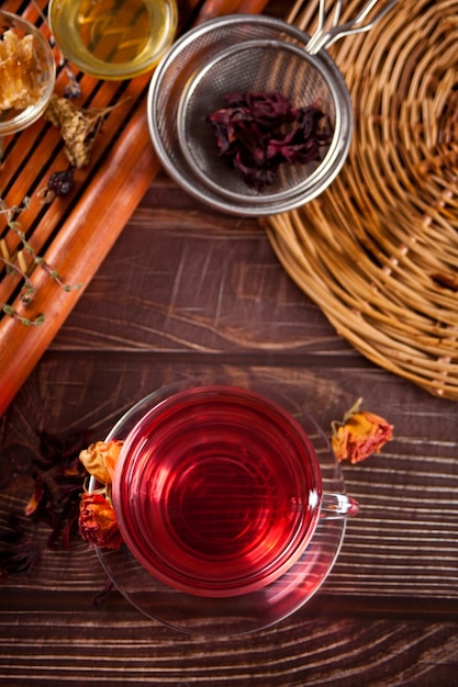 Чашка травяного красного чая с сухими розами и гибискусом