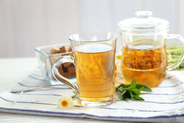 Cup of herbal tea and chamomile flower on table